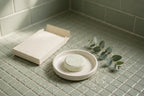 Shower steamer tablet in a ceramic tray on a shower floor
