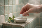 Hand placing a shower steamer tablet into a ceramic dish
