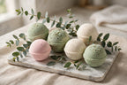 Pastel bath bombs arranged on a marble tray with eucalyptus