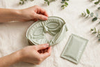 Nurtura Self-Heating Steam Eye Masks — hands unfolding a sage eye mask